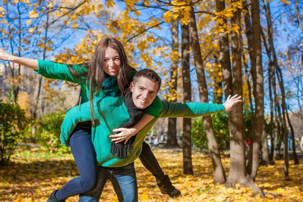 Casal feliz se divertindo no parque de outono em um dia ensolarado de outono — Fotografia de Stock