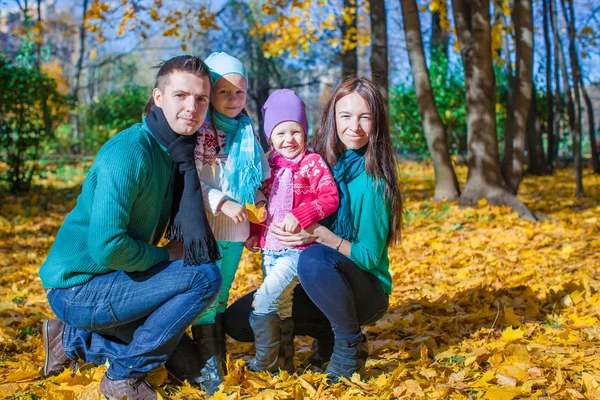 Молода сім'я з дівчатами літнього віку в осінньому парку в сонячний день — стокове фото