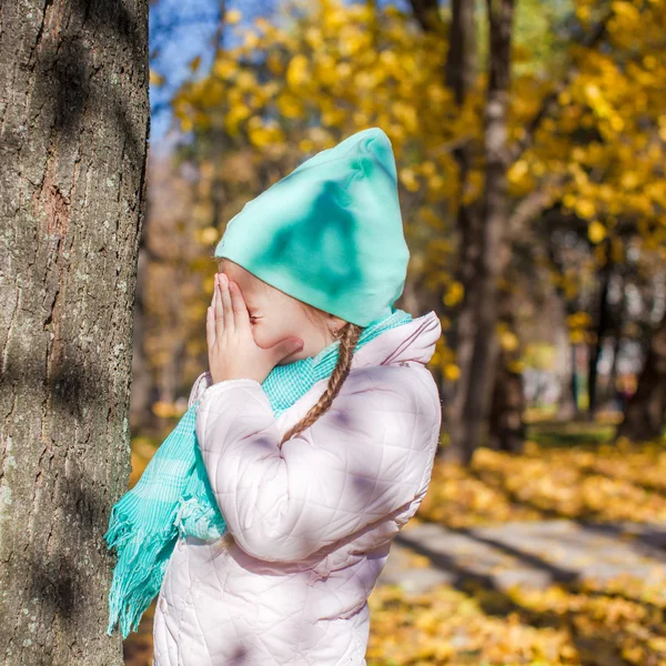 Niña jugando al escondite en el bosque otoñal — Foto de Stock
