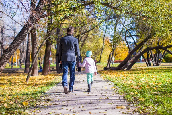 Вид на молодого отца и маленькую девочку, гуляющих в осеннем парке — стоковое фото