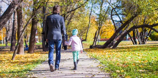 Вид на молодого отца и маленькую девочку, гуляющих в осеннем парке — стоковое фото