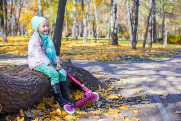 Liten flicka med skoter i höst park — Stockfoto