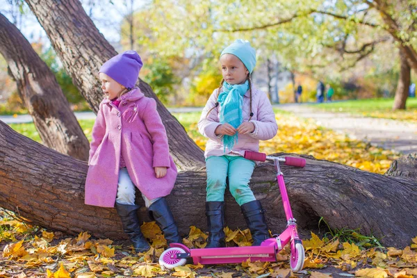 Little beautiful girl with scooter in the autumn park — Stock Photo, Image