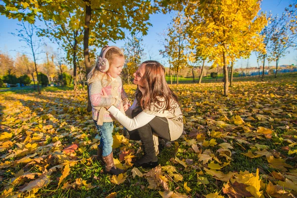 Lilla bedårande flicka och ung mamma i höst park på solig dag — Stockfoto