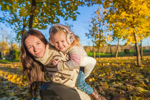 Retrato de menina bonito e mãe feliz se divertir na floresta de outono amarelo em um dia ensolarado quente — Fotografia de Stock