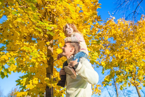 Bambina con padre felice divertirsi nel parco autunnale in una giornata di sole — Foto Stock