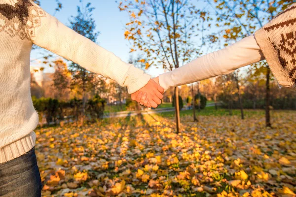 Main féminine et masculine sur fond de feuilles d'automne — Photo
