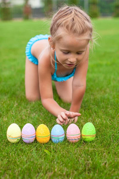 Pequena menina adorável segurando um ovo de Páscoa na grama — Fotografia de Stock