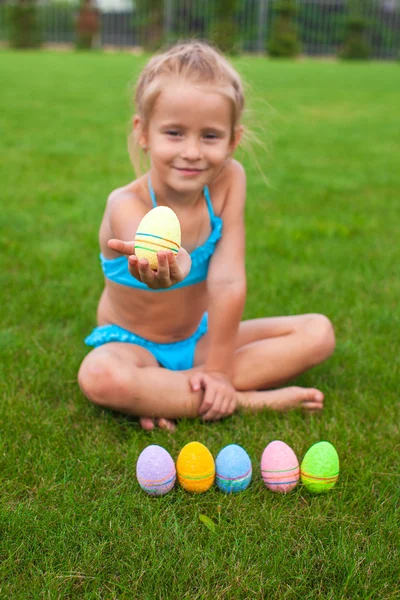 Paskalya yumurta çimenlerin üzerinde tutan küçük sevimli kız — Stok fotoğraf