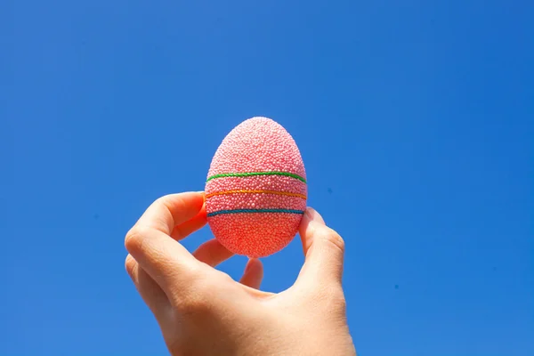 Bright Beautiful Easter egg in hand on background of blue sky — Stock Photo, Image