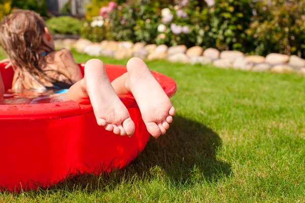 Gros plan des jambes d'une petite fille dans une petite piscine rouge — Photo