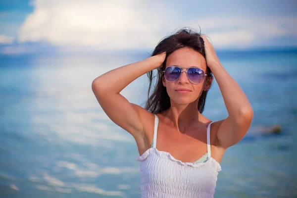 Schönes junges Mädchen, das am Strand steht und in die Kamera schaut — Stockfoto