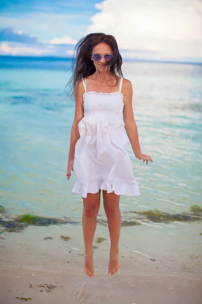 Happy young woman jumping near the water at beach and looking in camera — Stock Photo, Image