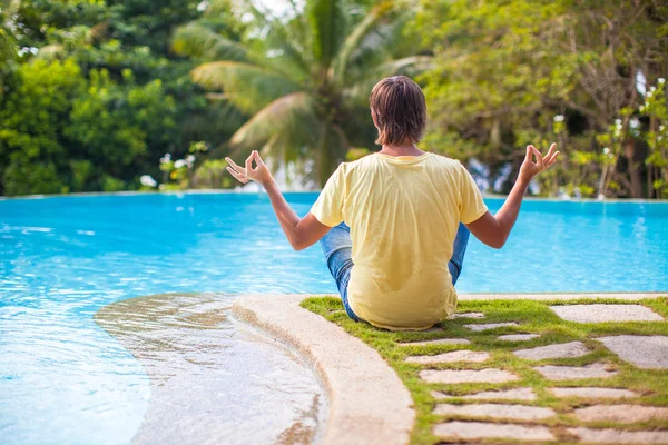 Back view of Man sitting in lotus position near the swimming pool — Stock Photo, Image