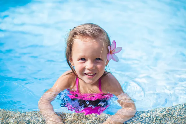 可爱的小女孩在游泳池里她耳朵后面的花 — 图库照片