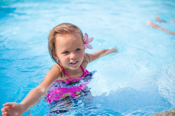 Piccola ragazza carina felice con fiore dietro l'orecchio si diverte in piscina — Foto Stock