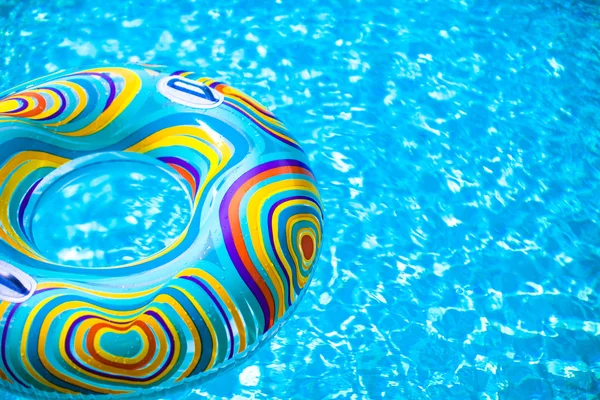 Anillo de goma colorido inflable flotando en la piscina azul — Foto de Stock
