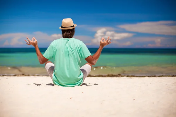 Young man sitting in lotus position on white sand beach — Stock Photo, Image