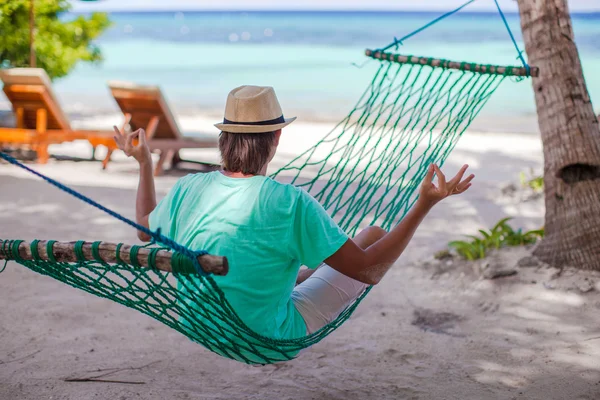 Young man sitting in hat on the lotus position at hammock — Stock Photo, Image