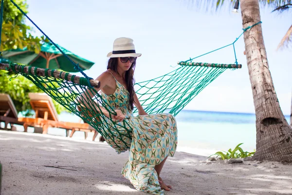 Счастливая молодая женщина отдыхает в гамаке на тропическом пляже — стоковое фото