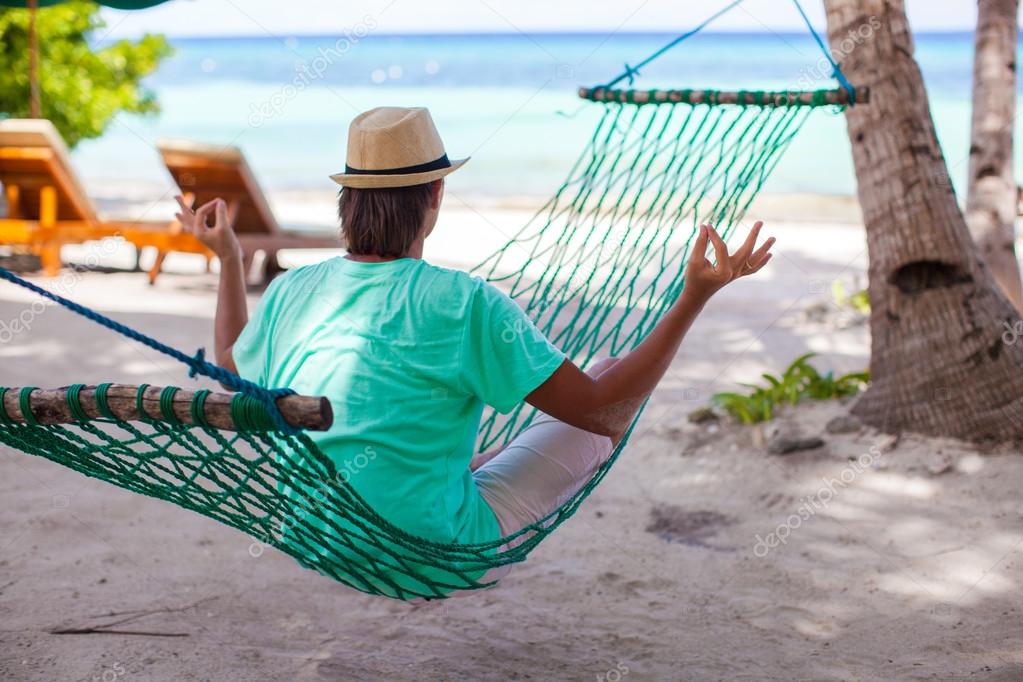 Young man sitting in the lotus position at hammock