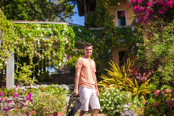 Young man in a flower garden at the exotic resort — Stock Photo, Image