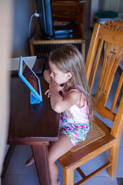 Menina sentada na mesa e olhando desenhos animados — Fotografia de Stock