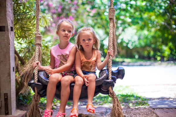 Meninas balançando em um acolhedor lindo pátio florido — Fotografia de Stock