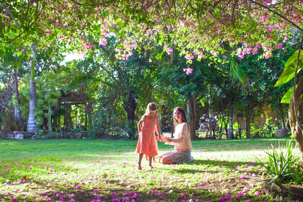 Menina com a mãe sentada no exuberante jardim e desfrutar de descanso de verão — Fotografia de Stock