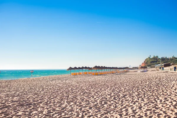Playa vacía con sombrillas cerradas por la mañana temprano en la costa portuguesa —  Fotos de Stock