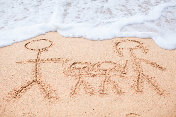 Family of four drawing on the beach