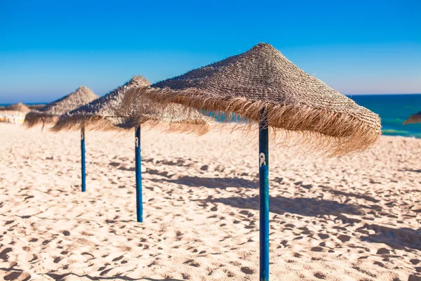 Straw umbrellas at empty tropical beach on the Atlantic coast — Stock Photo, Image