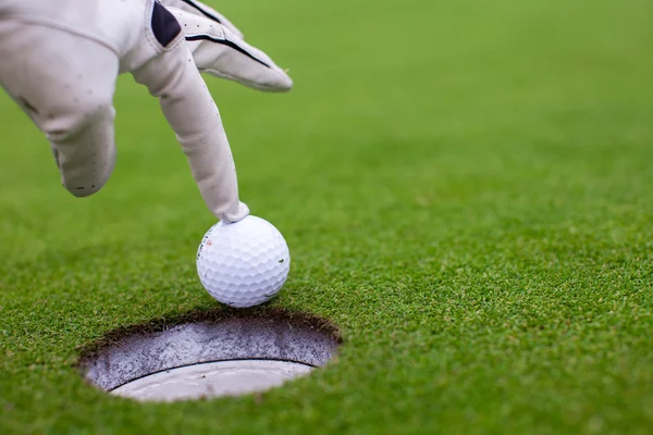 La mano dell'uomo che mette una palla da golf nel buco sul campo verde — Foto Stock