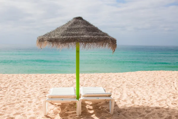 Strand ligstoelen en parasols op het exotische resort aan woestijn kust — Stockfoto