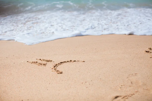 Sorriso triste desenhando na areia na praia tropical — Fotografia de Stock