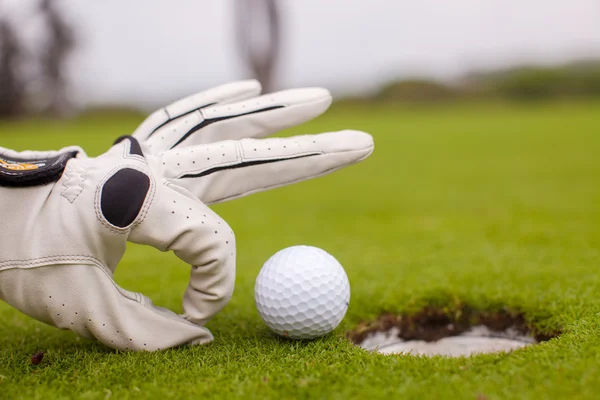 Giocatore di golf uomo spingendo pallone da golf nel buco — Foto Stock