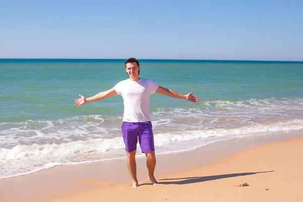 Jonge man verspreid zijn handen op tropisch strand — Stockfoto