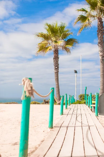 Wooden scaffold on way to the sea of palm trees at white beach — Stock Photo, Image