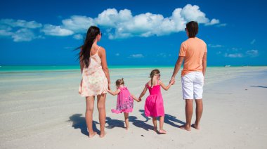 Young beautiful family with two daughters having fun at beach