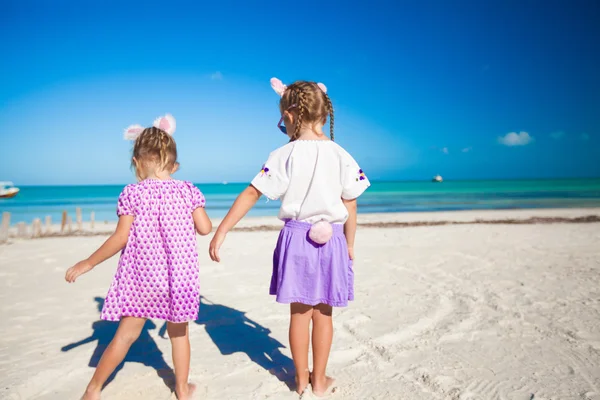 Две милые девочки в пасхальных ушах веселятся на экзотическом пляже — стоковое фото