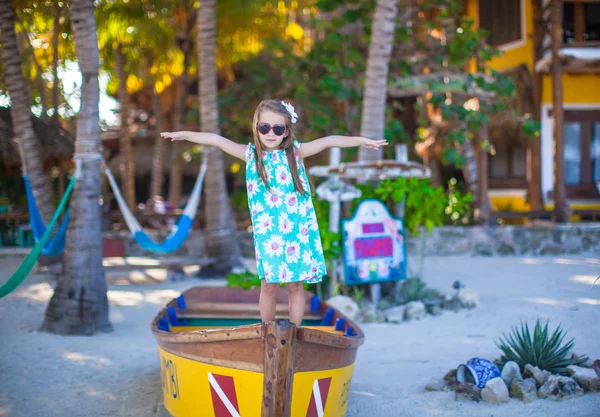Little beautiful girl in a boat on the beach at exotic resort — Stock Photo, Image