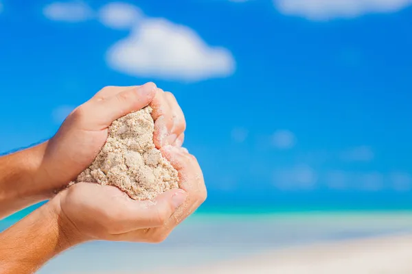 Man handen houden witte tropische strand vorm hart vorm achtergrond de zee — Stockfoto