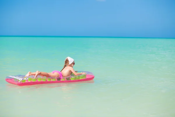 Schattig meisje ontspannen op roze lucht-bed in warme zee — Stockfoto