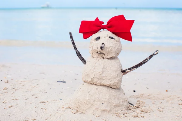 Little sandy snowman with bow on white Caribbean beach — Stock Photo, Image