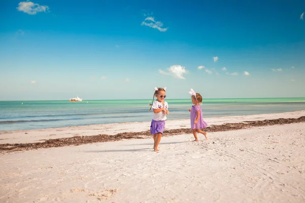 Dos niñas lindas en orejas de Pascua se divierten en la playa exótica —  Fotos de Stock