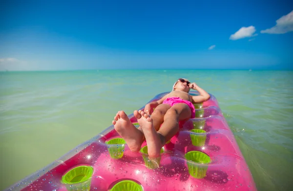 Kleines süßes Mädchen auf rosa Luftmatratze sonnt sich in der Karibik — Stockfoto