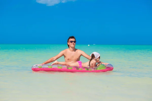 Young father with cute daughter on an air mattress in the sea — Stock Photo, Image