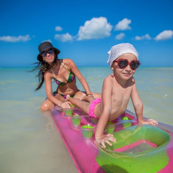 Niña con madre joven en un colchón de aire en el mar —  Fotos de Stock