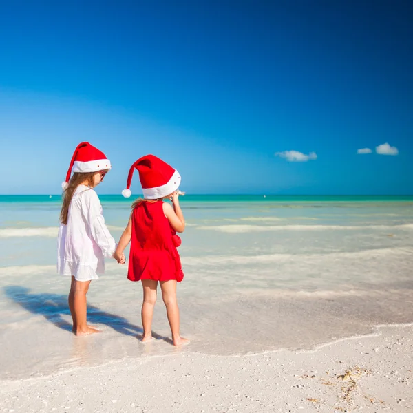 Rear view of Little cute girls in Christmas hats on the exotic beach — Stock Photo, Image