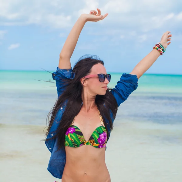 Jonge sexy vrouw in zwembroek en denim jasje veel plezier op het strand — Stockfoto